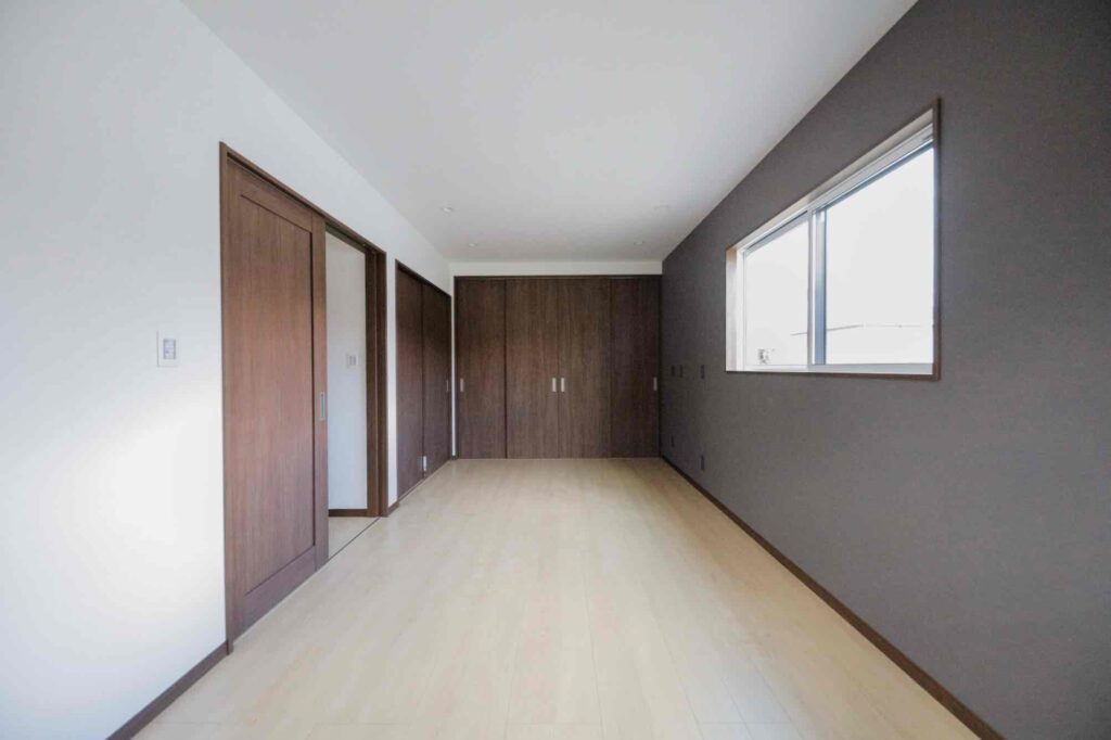 山梨平屋専門店が施工した、ダークカラーのアクセントクロスと木目建具が調和する平屋住宅の居室