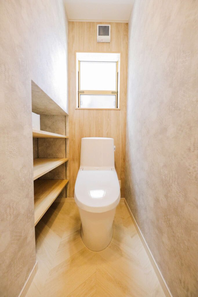 当社が施工した、木目調の壁とオープン棚が特徴のナチュラルな山梨平屋住宅のトイレ空間