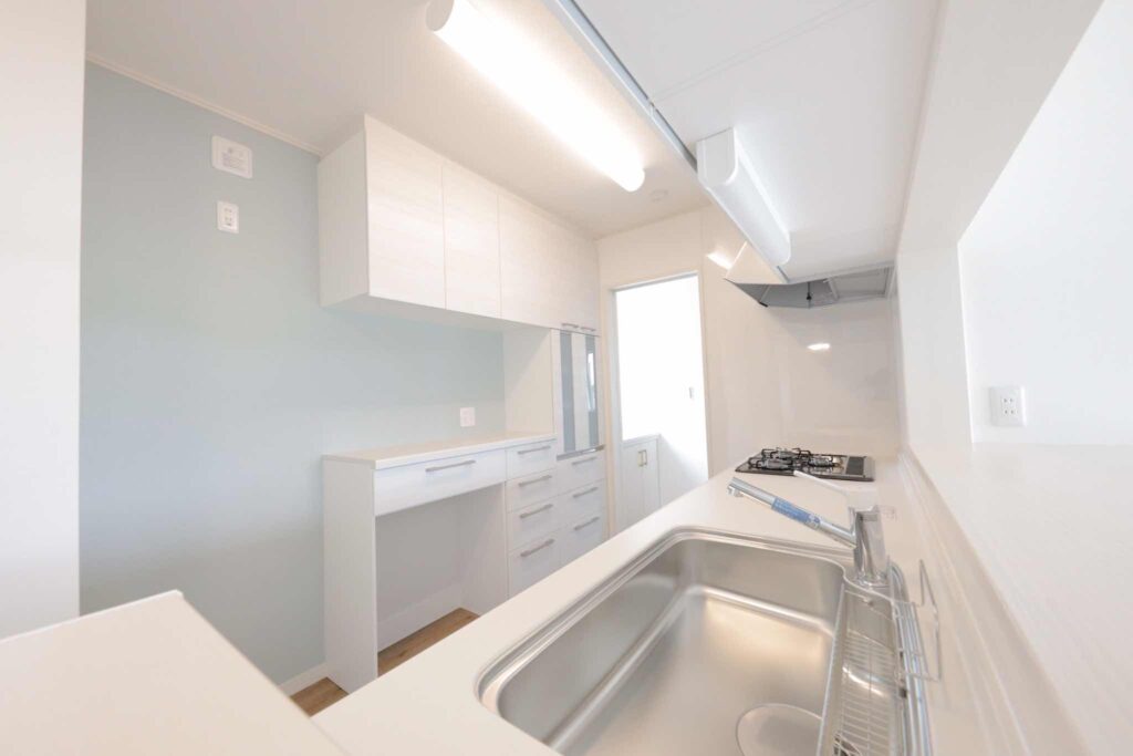 山梨平屋住宅に採用された対面キッチン。白を基調とし、淡いブルーのアクセントウォールが特徴の明るい空間。