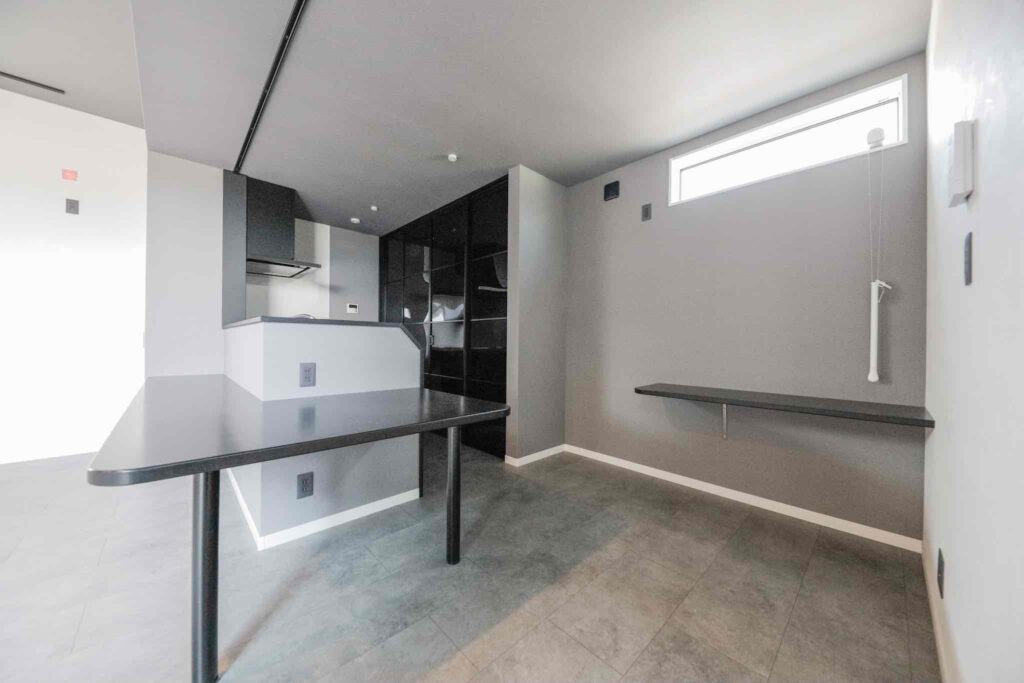 ダークトーンで統一された山梨平屋住宅のLDK。黒の扉付き背面棚と造作カウンターが特徴のスタイリッシュな空間デザイン