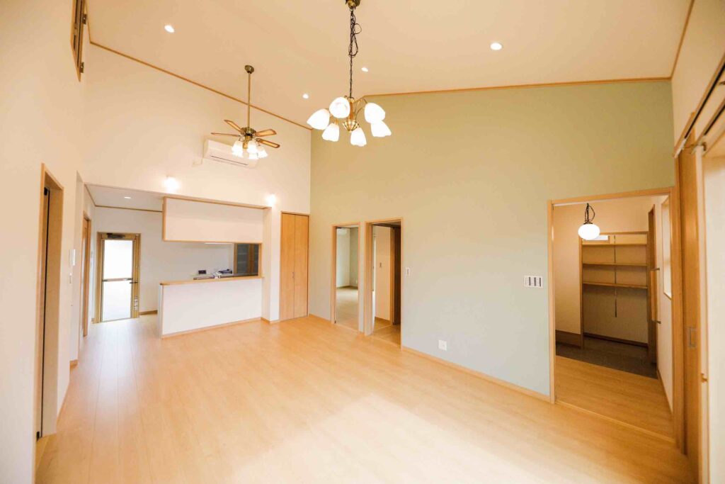 高天井のLDKと淡いグリーンのアクセントウォールが特徴の山梨平屋住宅。対面キッチンとWICへ続く動線が便利な施工事例。