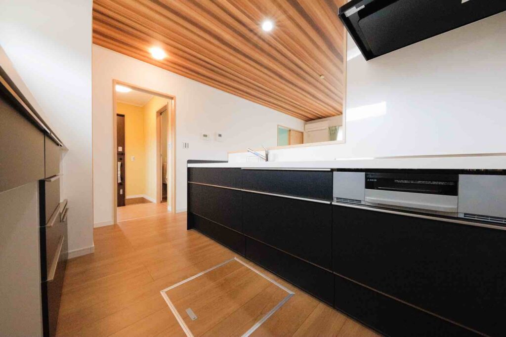 山梨平屋住宅の施工事例｜木目天井と黒い対面キッチンが特徴のキッチン空間