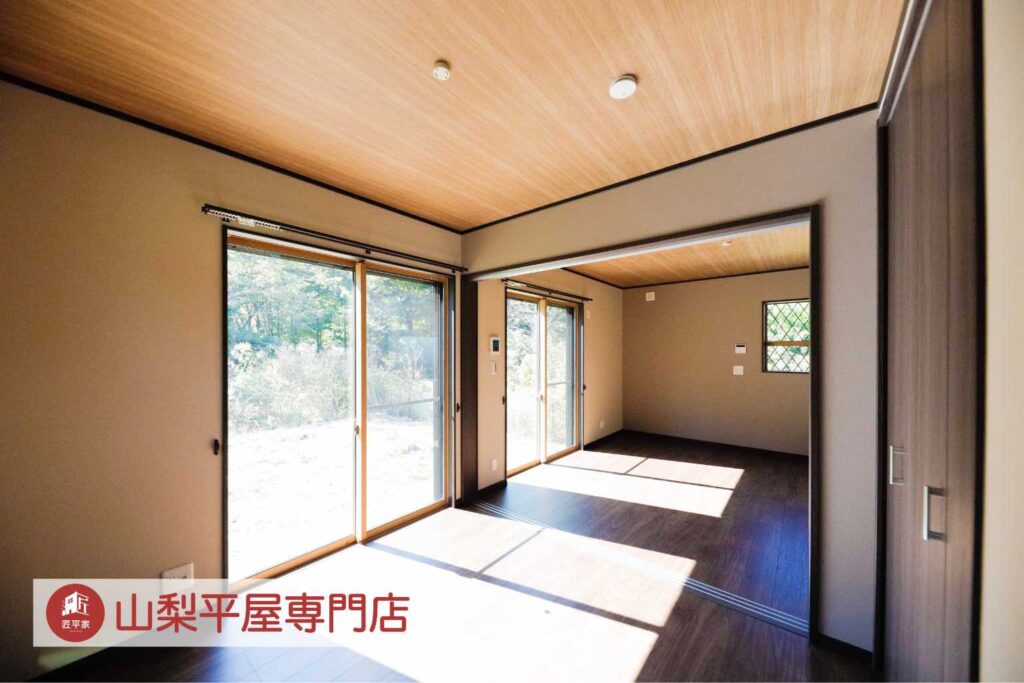 木目調の天井と大きな窓、隣接する空間との大開口がある山梨平屋住宅の施工事例