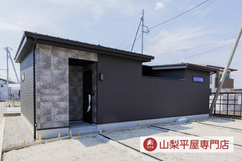 ダークカラーの玄関ドアを採用したモダンな山梨平屋住宅の施工事例