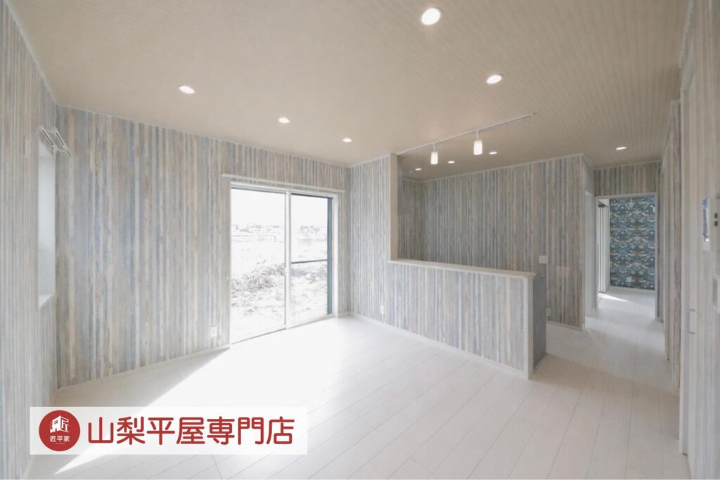 木目調クロスと白い床、対面キッチンを採用した明るい山梨平屋住宅のLDK施工事例